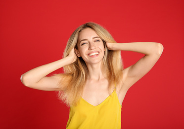 Photo of Portrait of beautiful young woman with blonde hair on red background