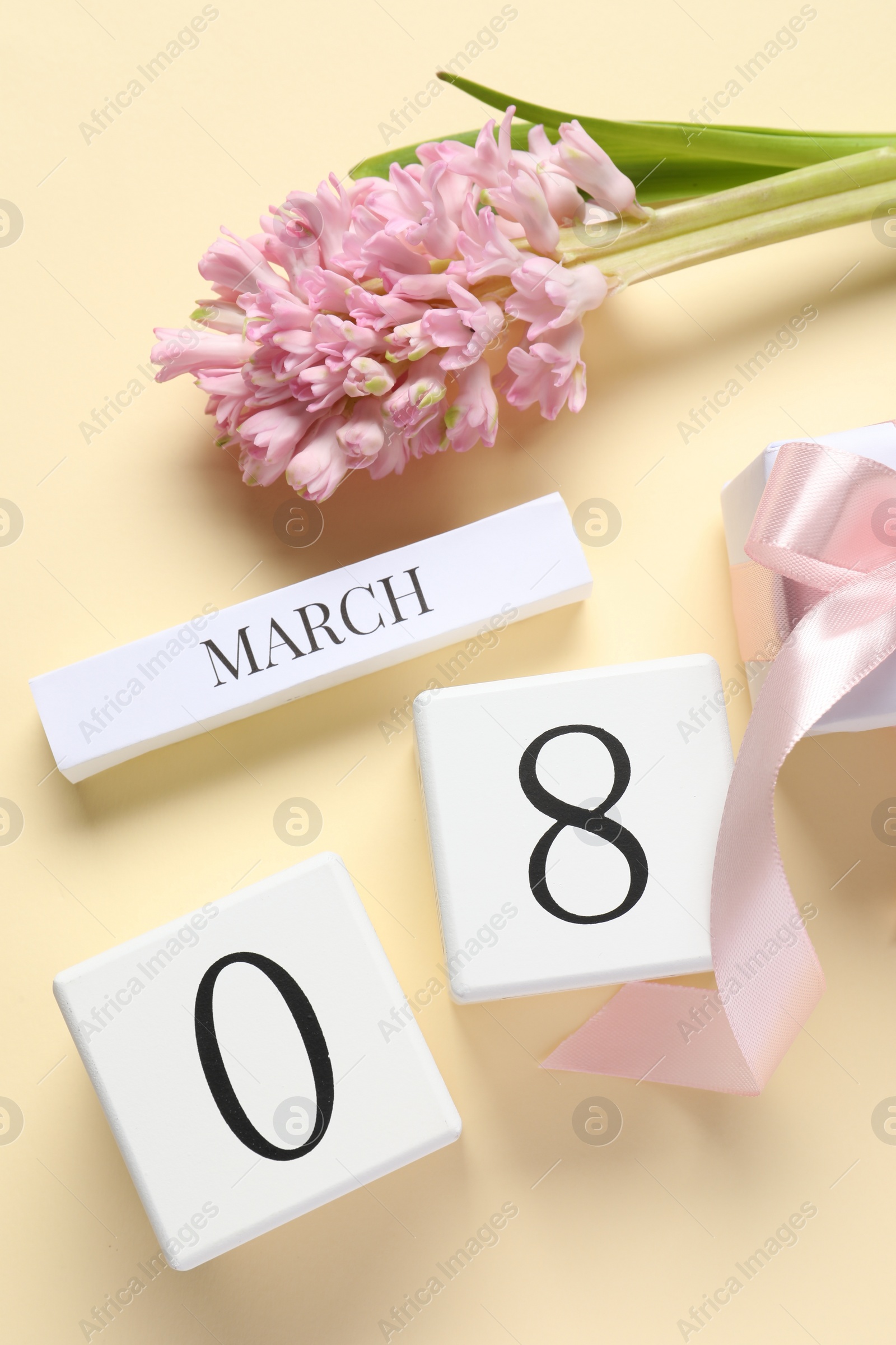 Photo of International Women's day - 8th of March. Gift box, wooden block calendar and beautiful flowers on beige background, flat lay