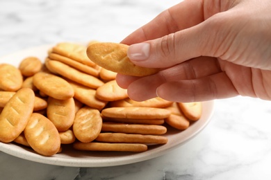 Photo of Woman taking delicious cracker from plate, closeup