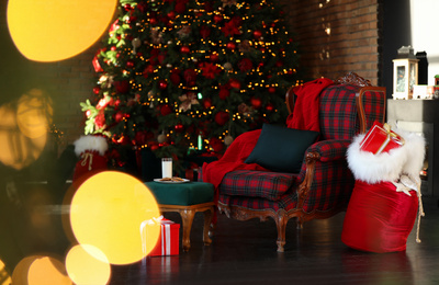 Photo of Santa Claus bag near armchair in room with Christmas tree