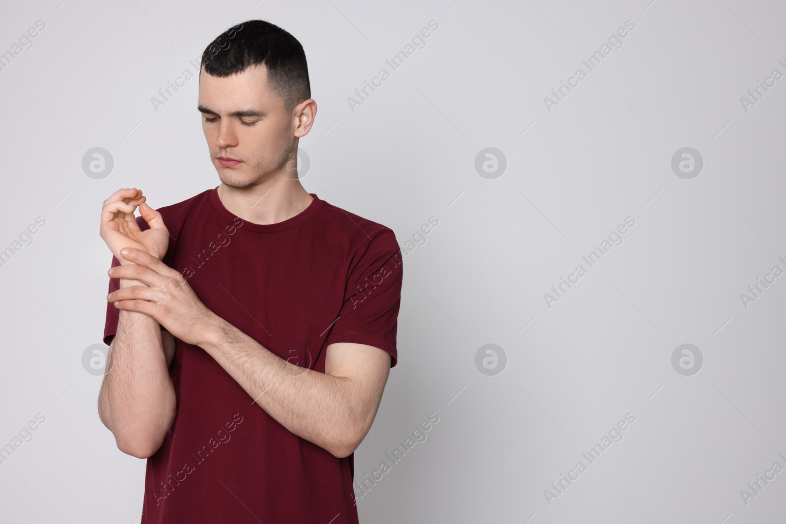 Photo of Man suffering from pain in his hand on light background, space for text. Arthritis symptoms