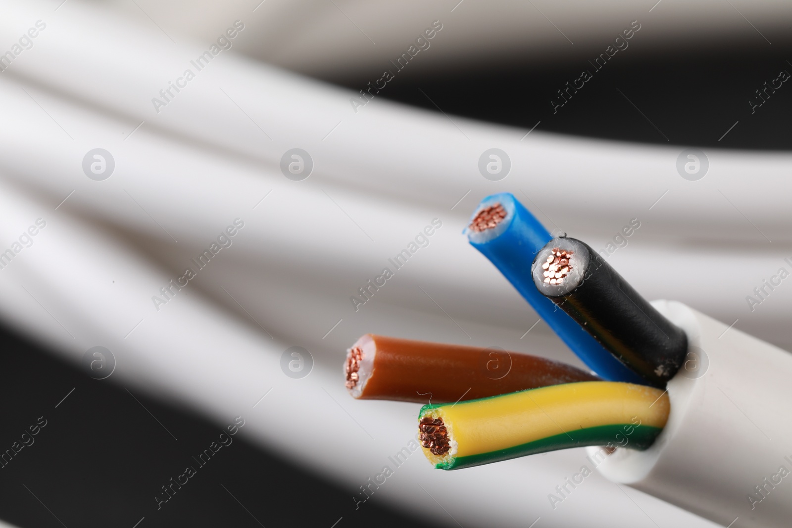 Photo of New colorful electrical wire on blurred background, closeup. Space for text