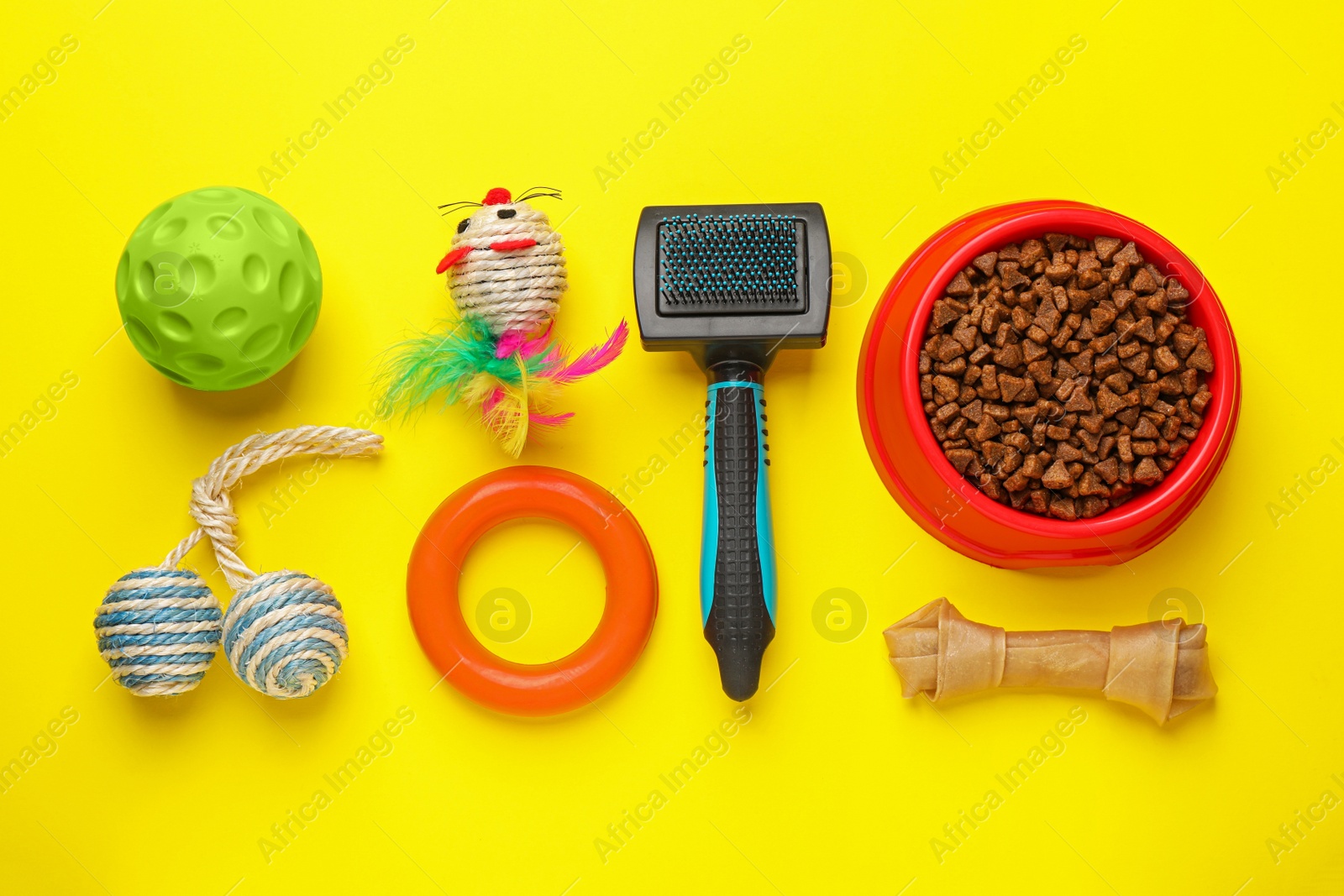 Photo of Flat lay composition with pet toys and feeding bowl on yellow background