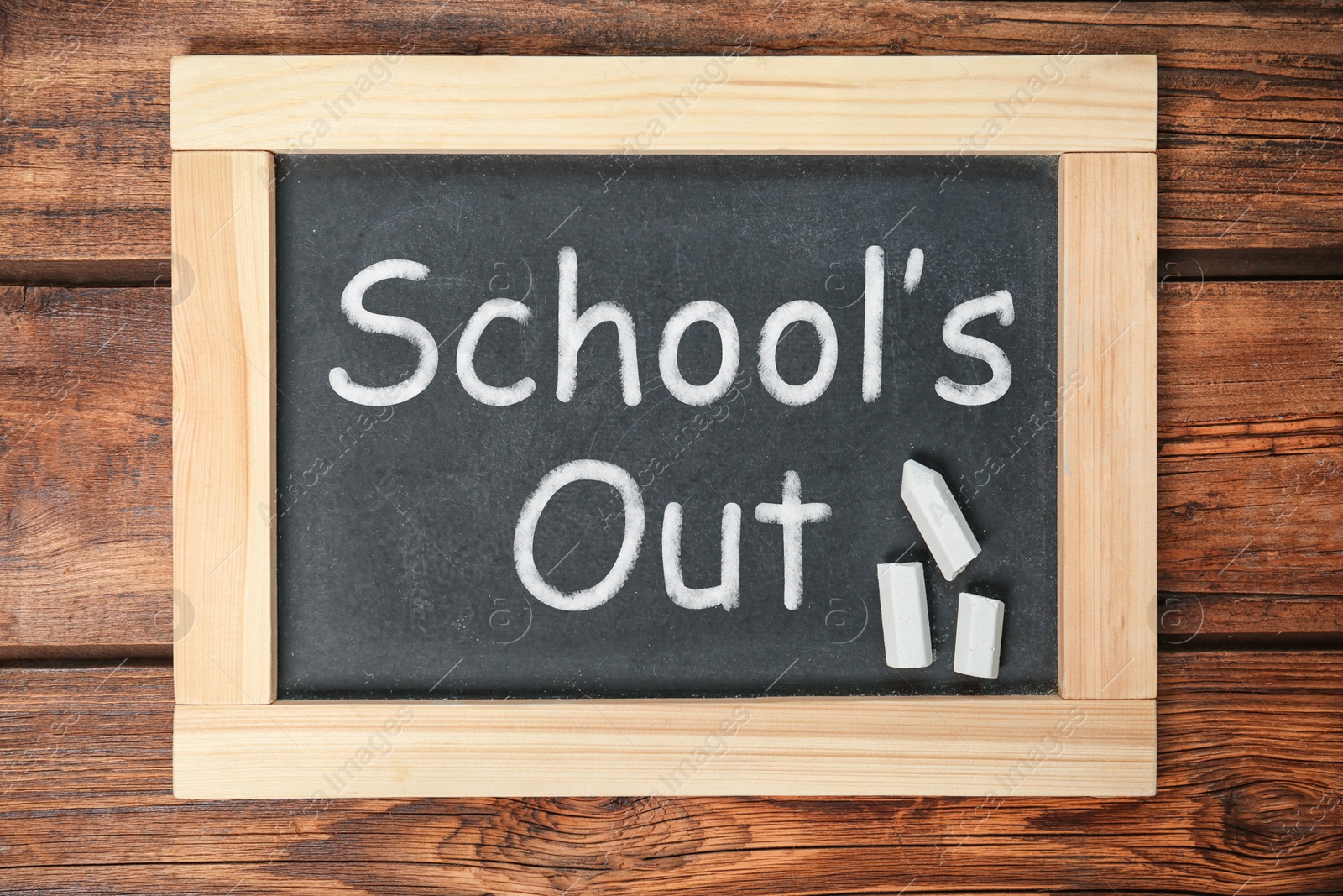 Image of Chalkboard with text SCHOOL'S OUT on wooden background, top view