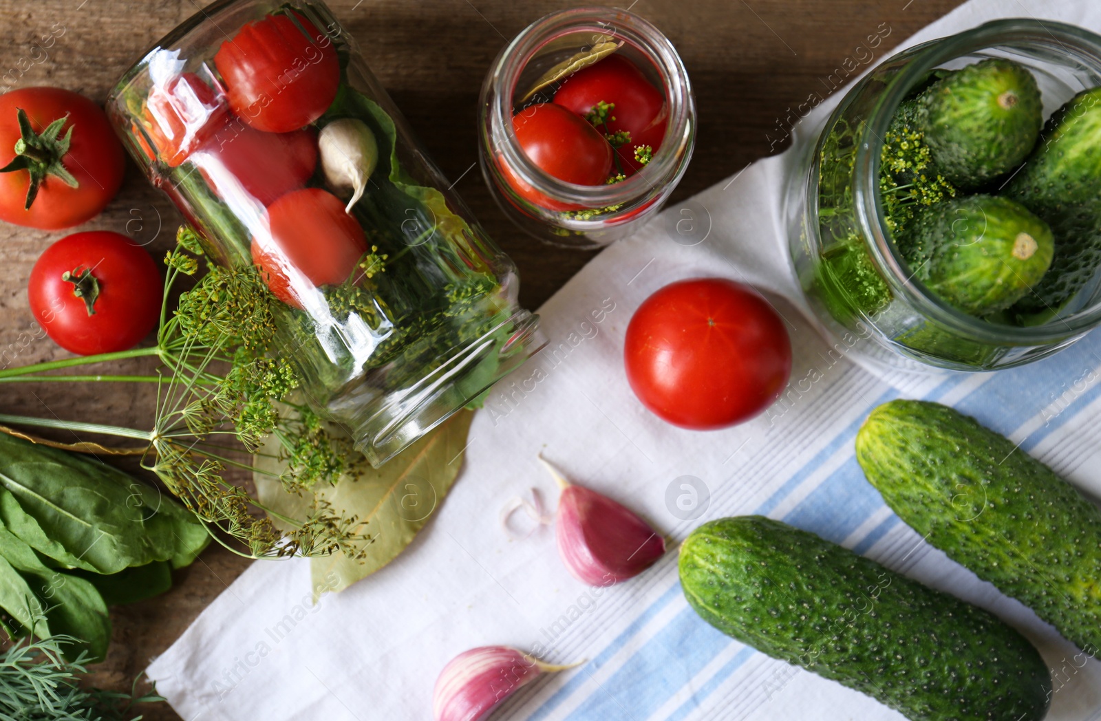 Photo of Glass jars, fresh vegetables and herbs on wooden table, flat lay. Pickling recipe