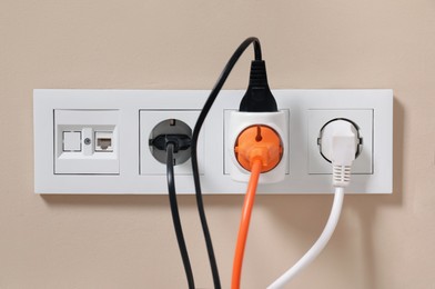 Photo of Many different electrical power plugs in sockets on beige wall