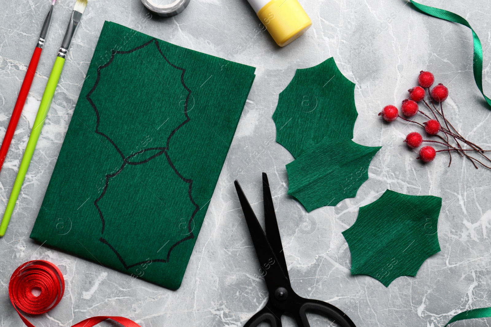 Photo of Set of instruments and materials for making mistletoe branch on grey table, flat lay