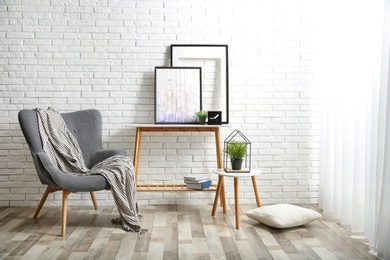 Photo of Stylish living room interior with comfortable armchair near brick wall. Space for text