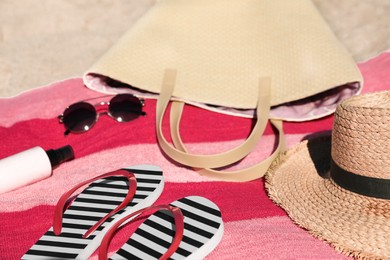 Striped flip flops, bag and other beach items on sand, closeup