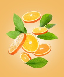 Image of Juicy orange slices and green leaves flying on pale orange background