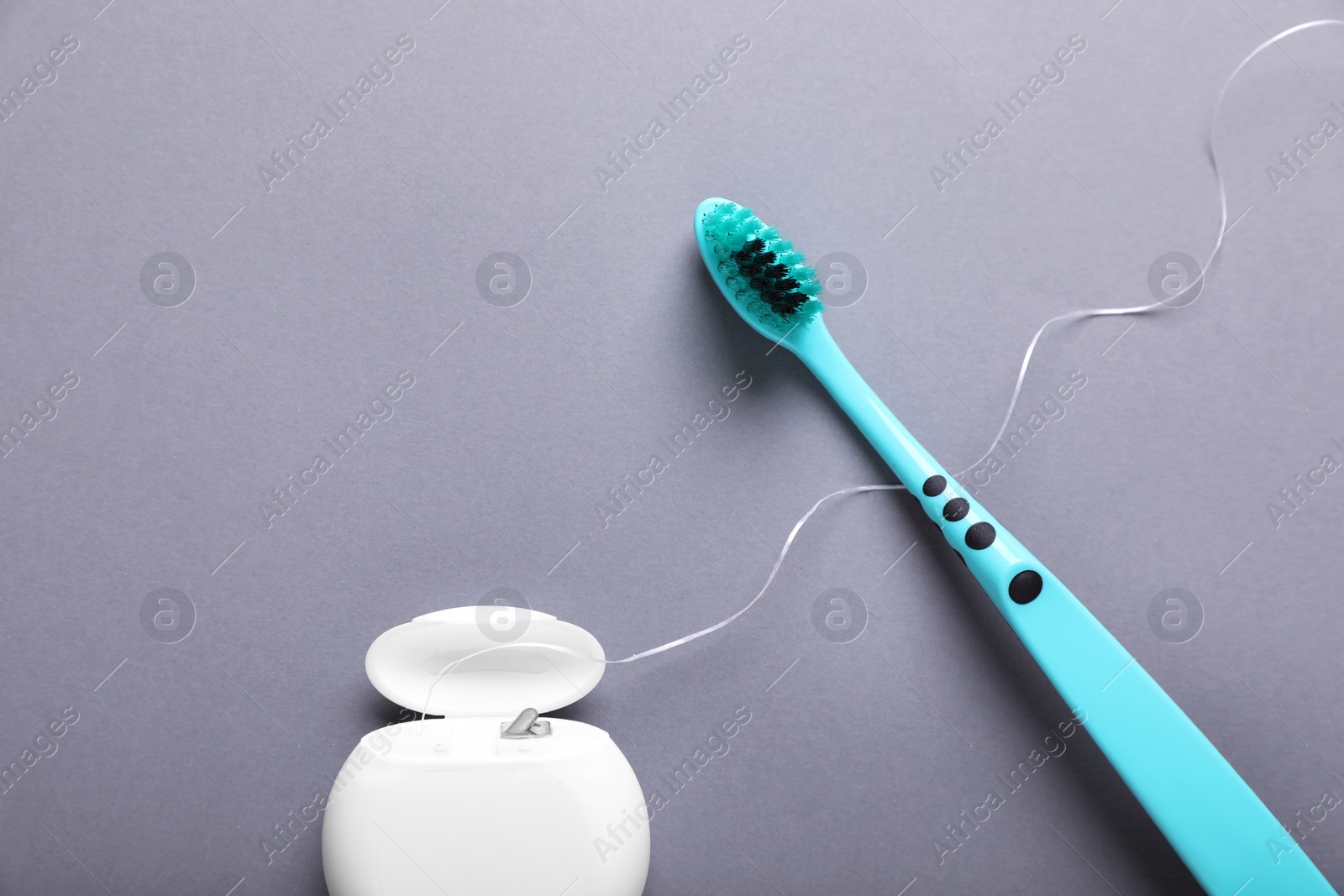 Photo of Container with dental floss and toothbrush on light grey background, flat lay