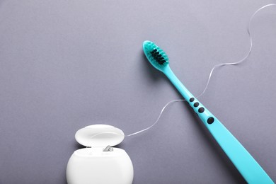 Photo of Container with dental floss and toothbrush on light grey background, flat lay