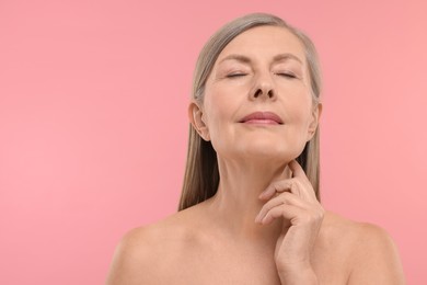 Beautiful woman touching her neck on pink background, space for text