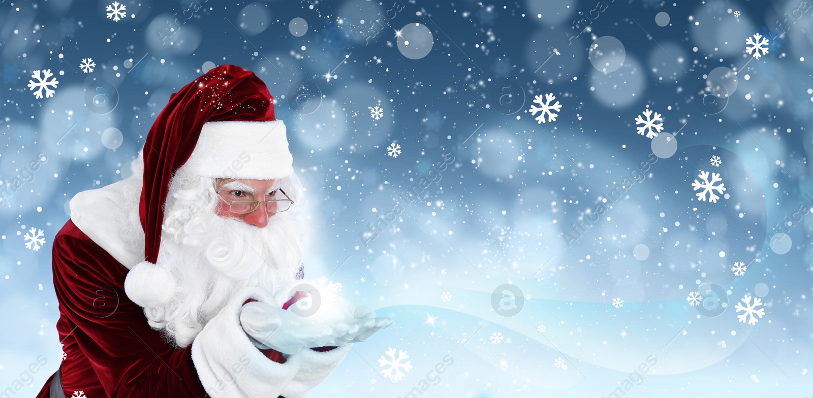 Image of Santa Claus blowing magic snow around, bokeh effect. Space for text