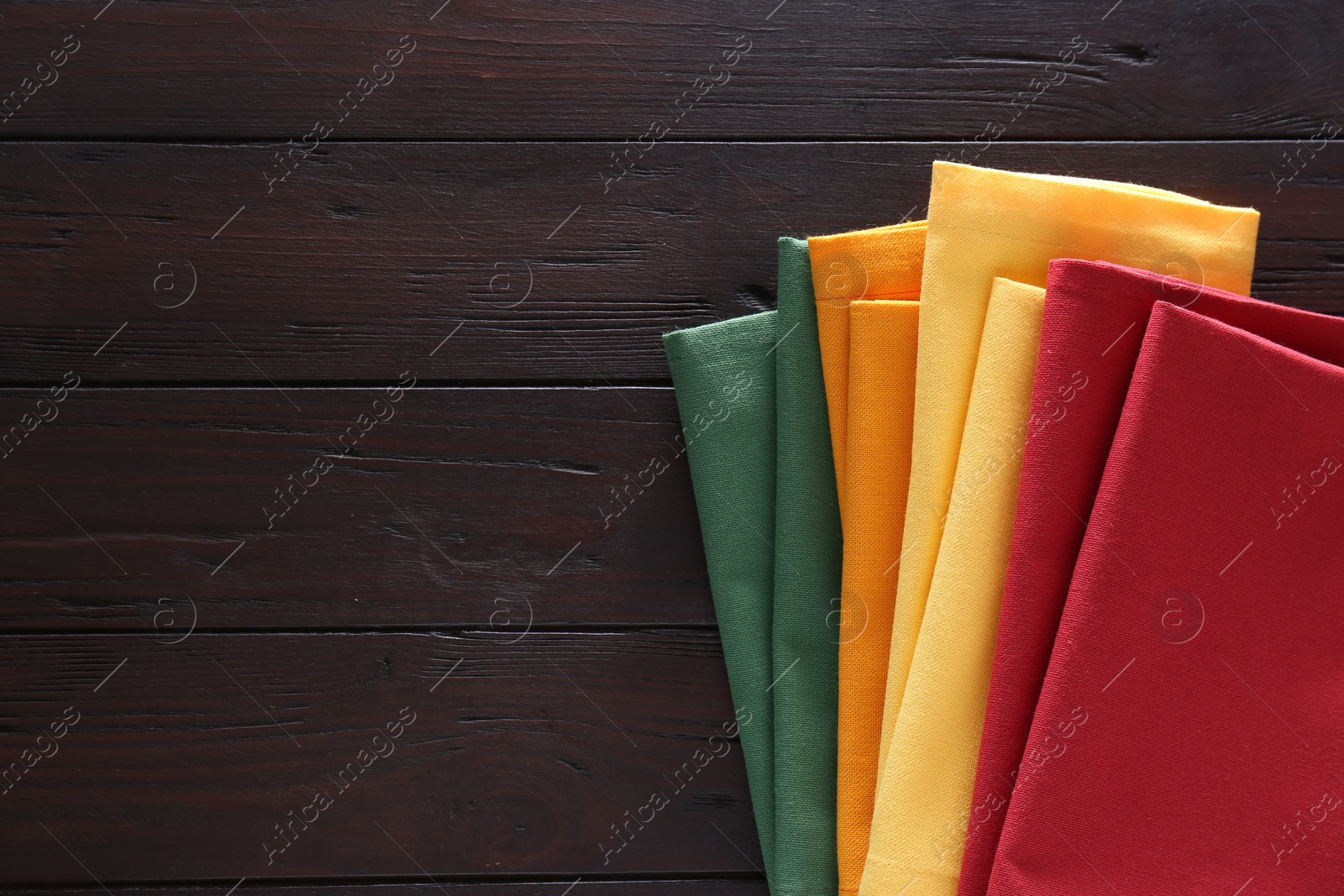 Photo of Different colorful napkins on wooden table, top view. Space for text