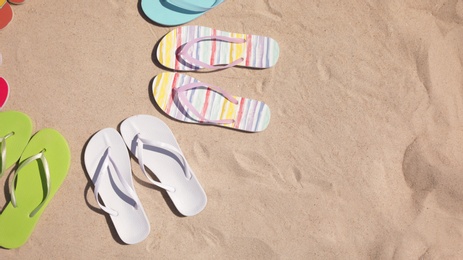 Photo of Flat lay composition with flip flops on sand, space for text. Summer beach accessories
