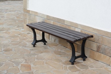 Wooden bench near wall with stone fragments outdoors