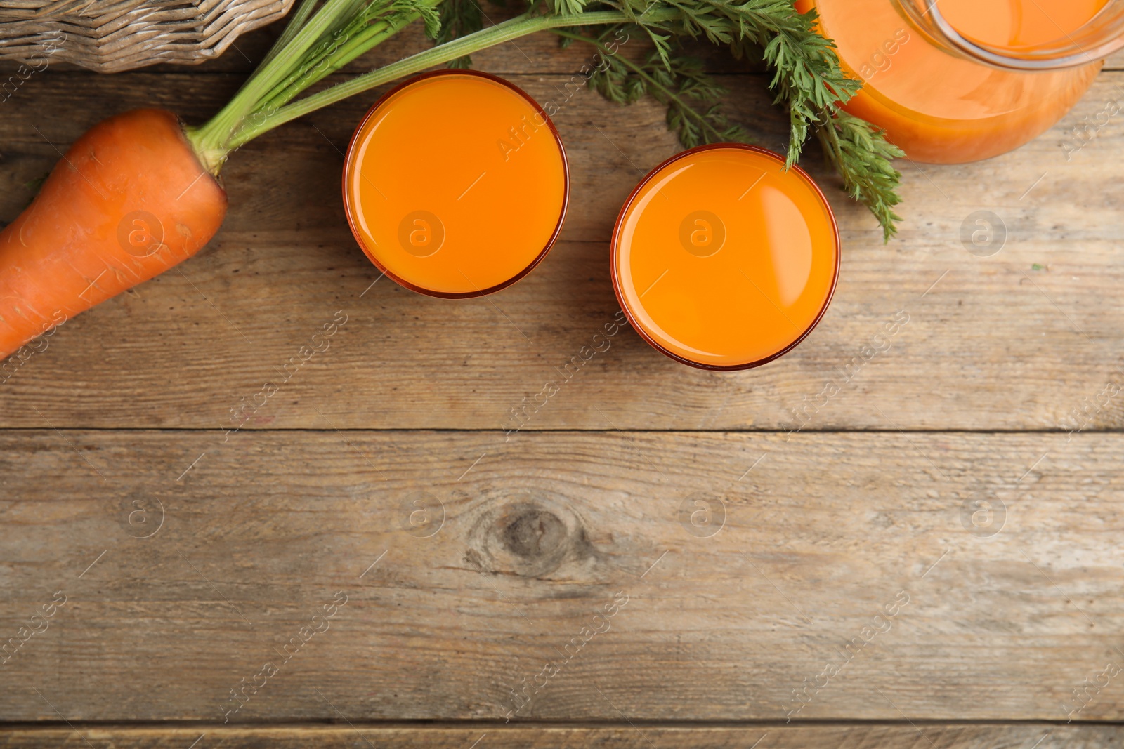 Photo of Freshly made carrot juice on wooden table, flat lay. Space for text