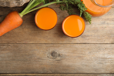 Photo of Freshly made carrot juice on wooden table, flat lay. Space for text