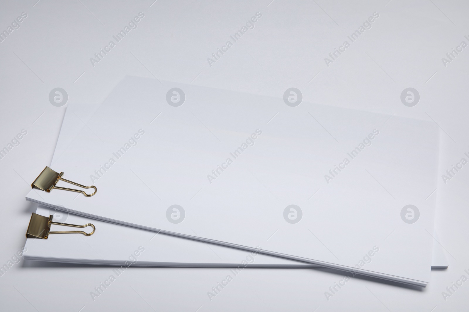 Photo of Sheets of paper with clips on white background