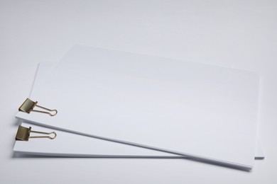 Photo of Sheets of paper with clips on white background