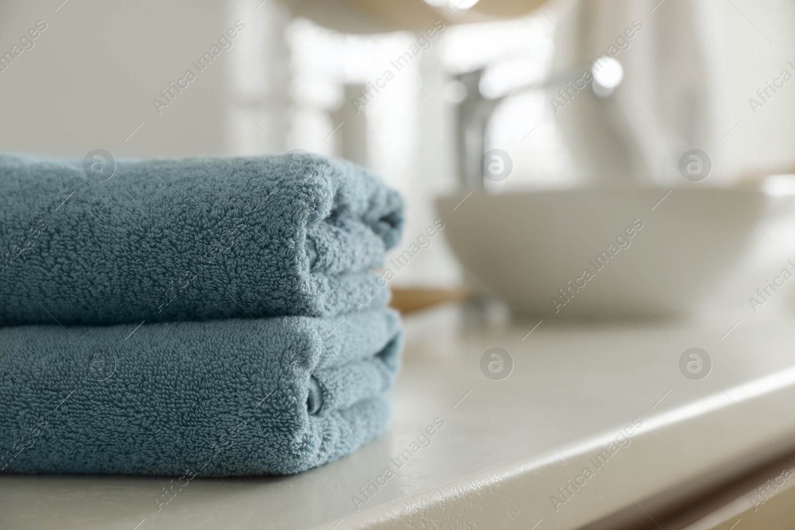 Photo of Stack of clean towels on countertop in bathroom. Space for text