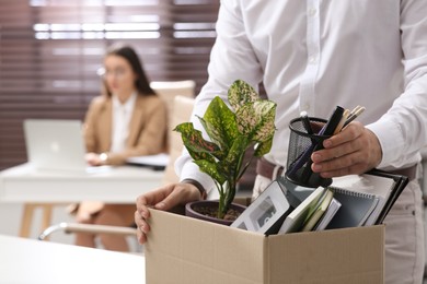 Photo of Dismissed man packing personal stuff into box in office, closeup