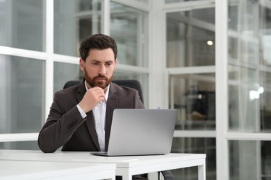 Man working on laptop at white desk in office. Space for text