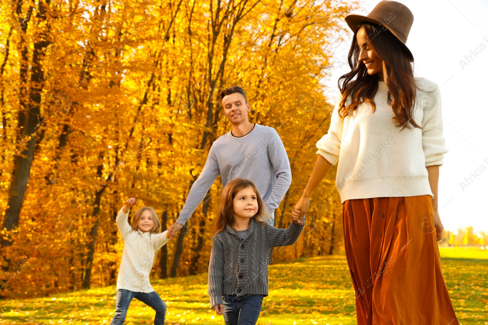 Photo of Happy family with little daughters walking in autumn park