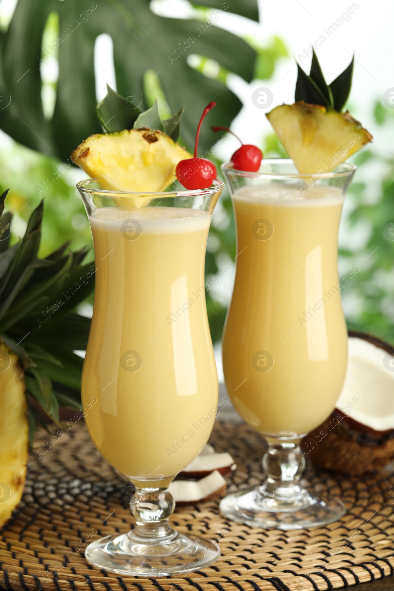 Photo of Tasty Pina Colada cocktails and ingredients on wicker mat
