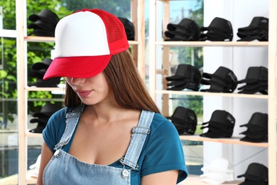 Young woman in blank colorful cap at store. Mock up for design