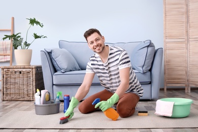 Photo of Mature man cleaning carpet at home