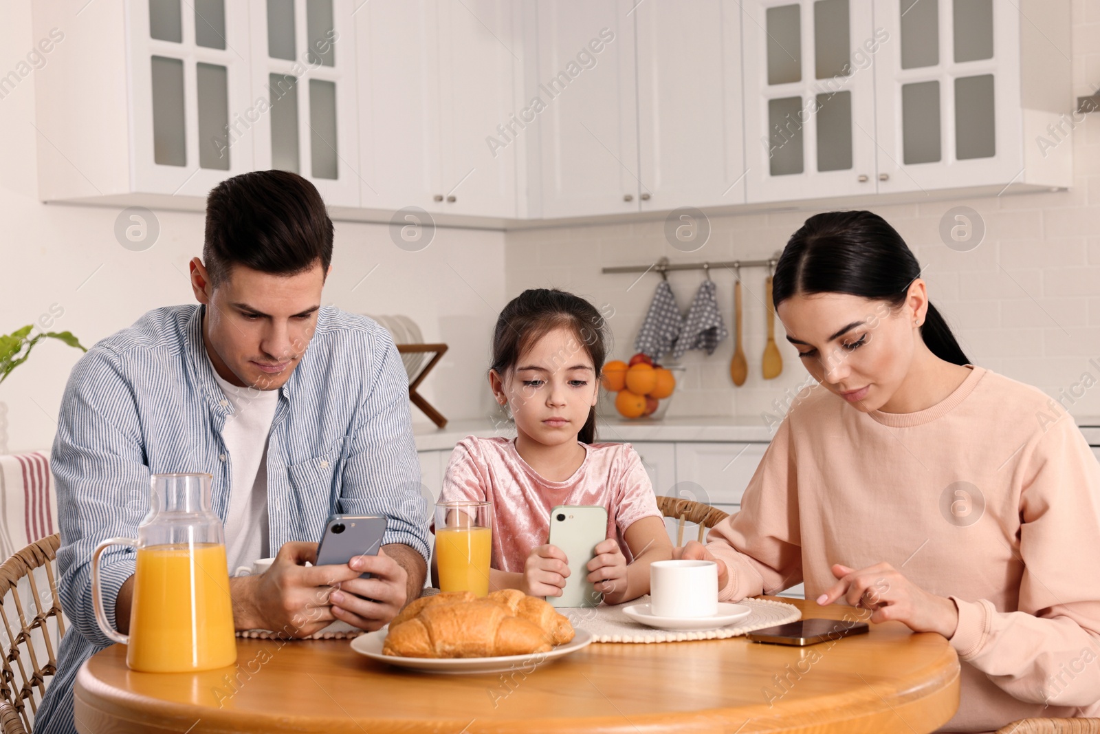 Photo of Internet addiction. Family with smartphones at table in kitchen