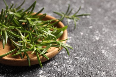 Photo of Fresh rosemary on grey textured table, closeup. Space for text