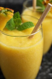 Tasty pineapple smoothie in glasses on table, closeup