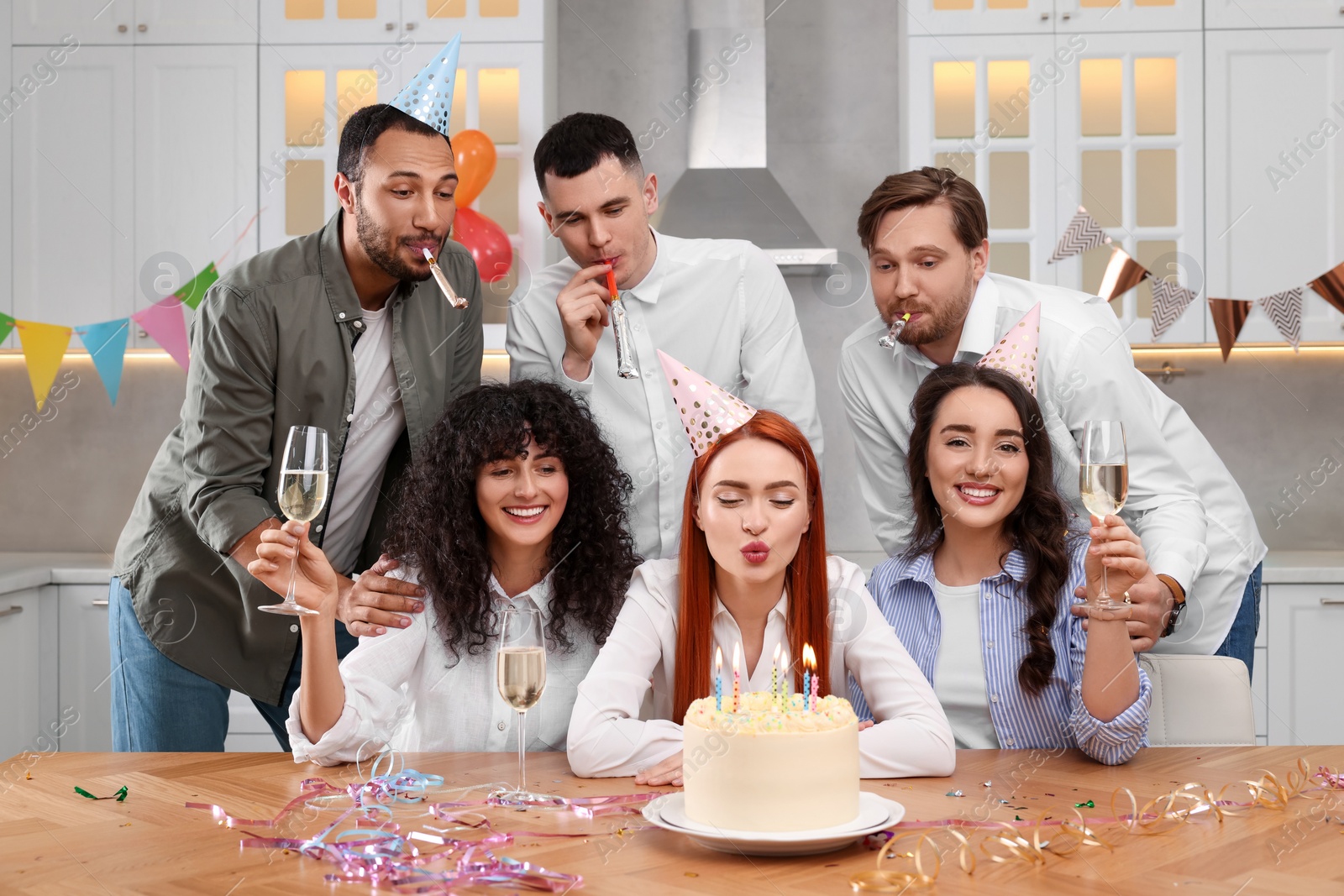 Photo of Happy friends with tasty cake celebrating birthday in kitchen