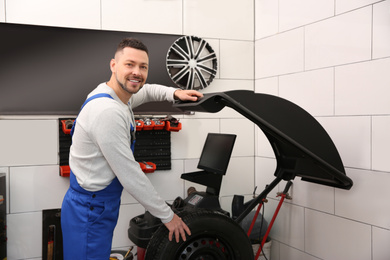 Photo of Mechanic working with wheel balancing machine at tire service