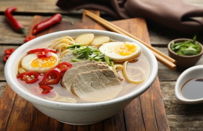 Delicious ramen in bowl on wooden table, closeup. Noodle soup