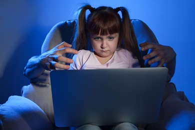 Stranger reaching little child with laptop on color background. Cyber danger