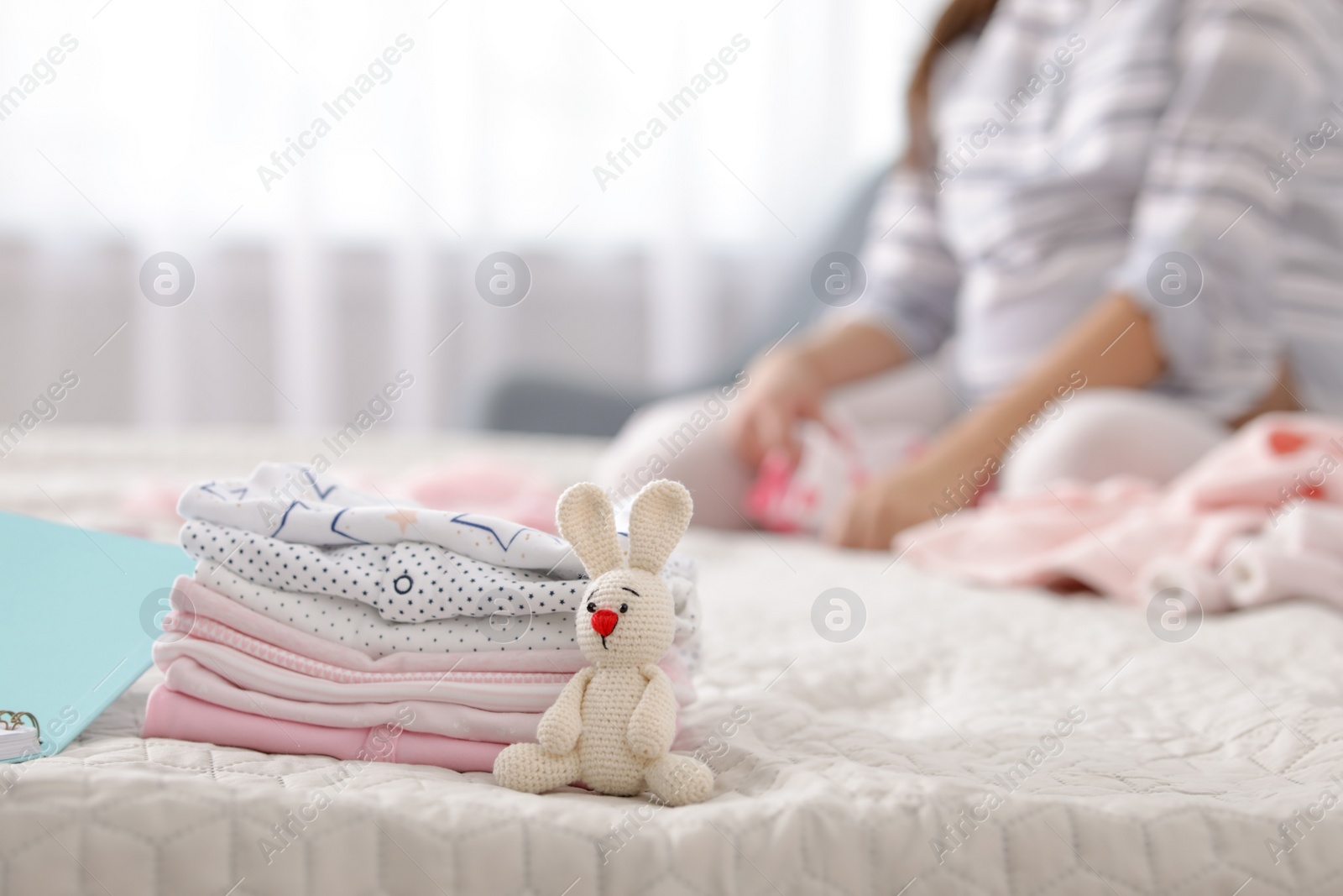 Photo of Baby clothes prepared for maternity hospital and pregnant woman on background