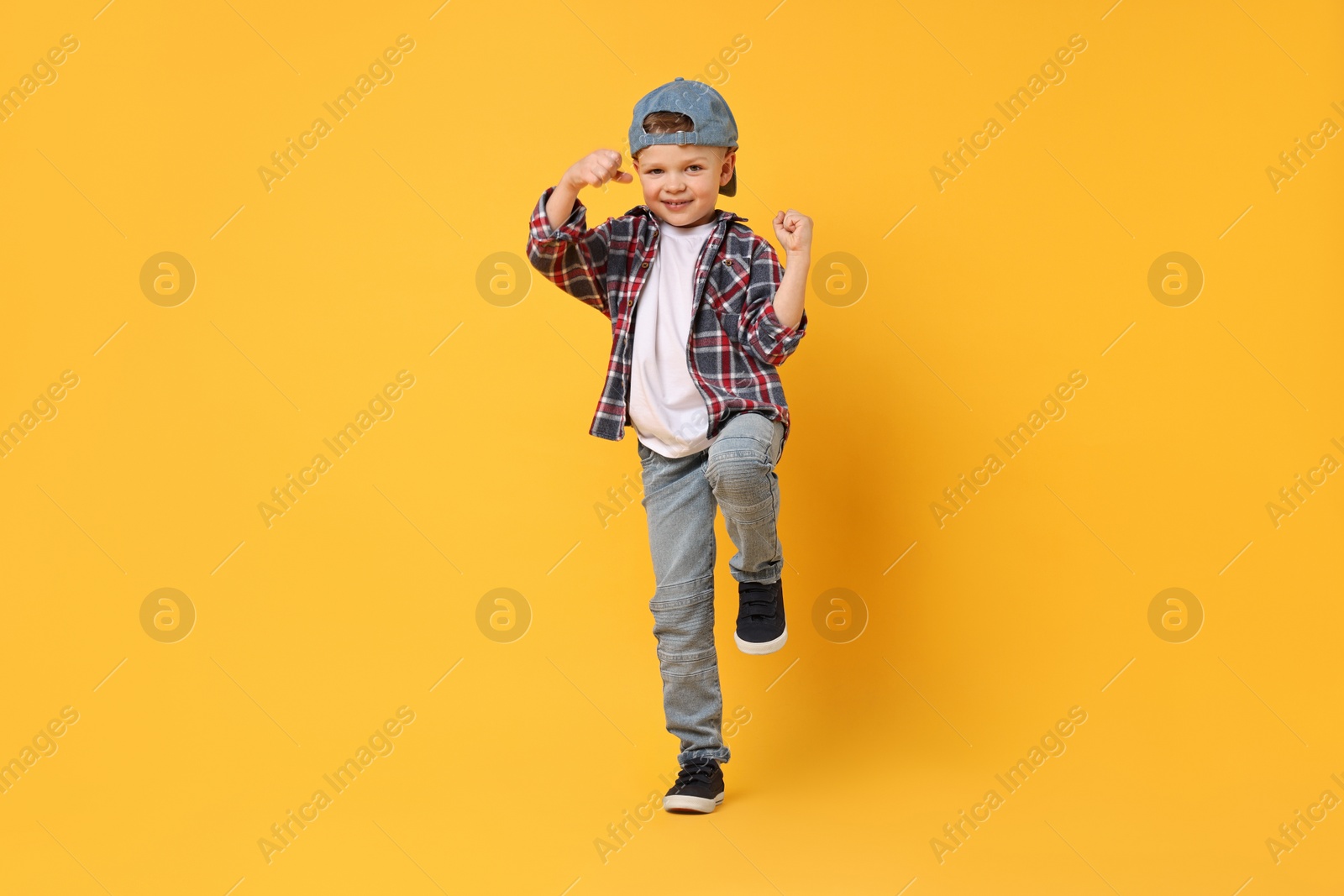 Photo of Happy little boy dancing on yellow background