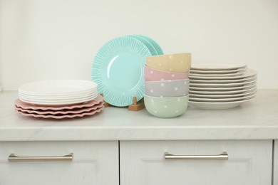 Clean plates and bowls on white marble countertop in kitchen