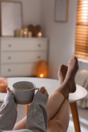 Woman with cup of aromatic coffee relaxing at home, closeup