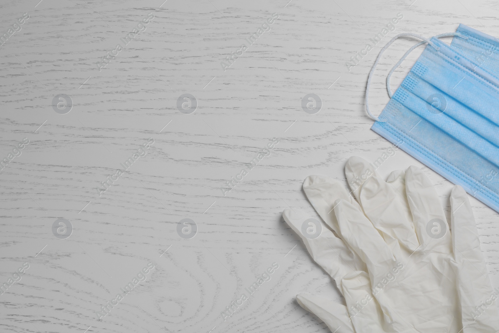 Photo of Protective masks and medical gloves on white wooden background, flat lay with space for text