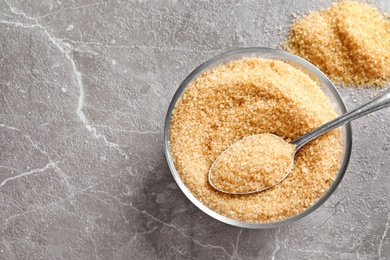 Spoon with brown sugar in bowl on table