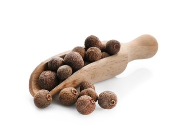 Wooden scoop with allspice pepper grains on white background