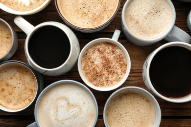 Many cups of different coffees on wooden table, flat lay