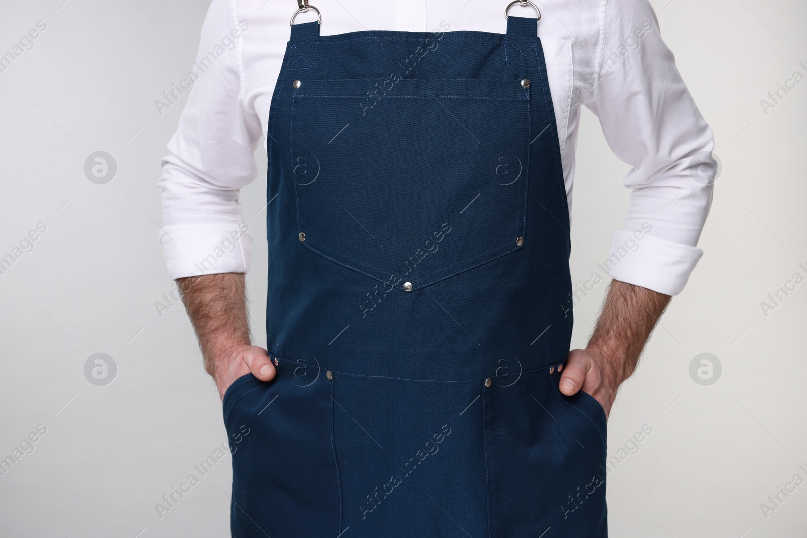 Photo of Man wearing kitchen apron on grey background, closeup. Mockup for design