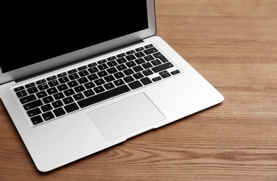 Photo of Modern laptop with blank screen on wooden table