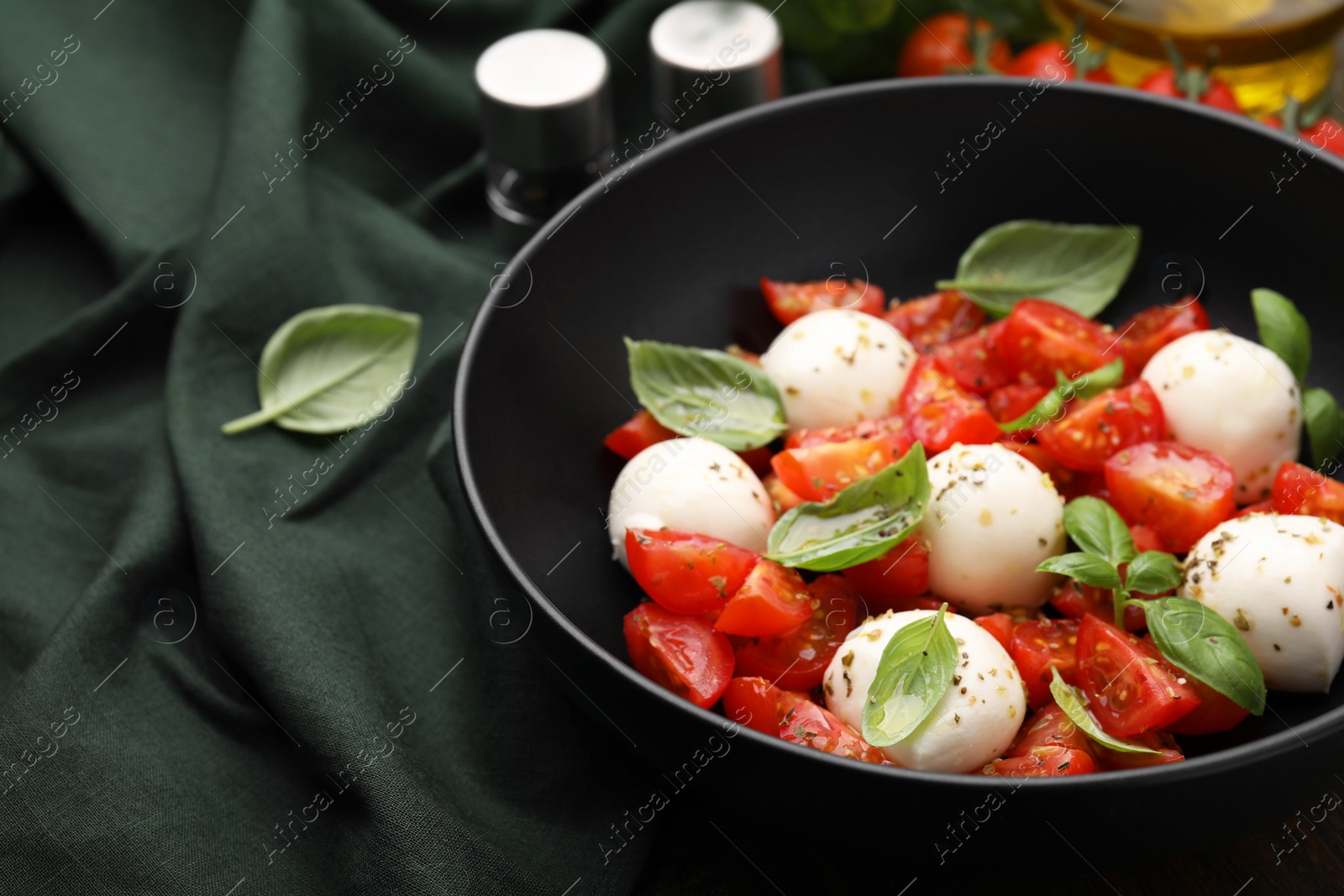 Photo of Tasty salad Caprese with tomatoes, mozzarella balls and basil on table, closeup. Space for text